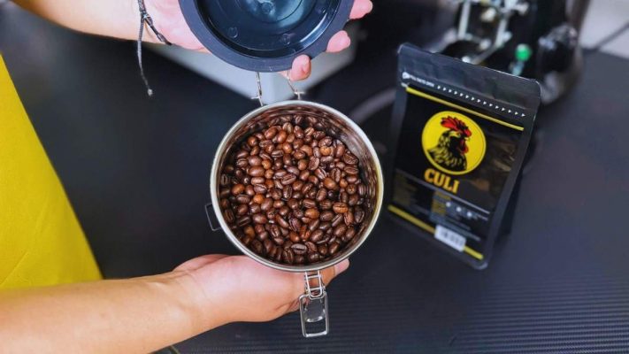 Tay đổ cà phê Culi Buôn Ma Thuột vào hũ kín khí để bảo quản.