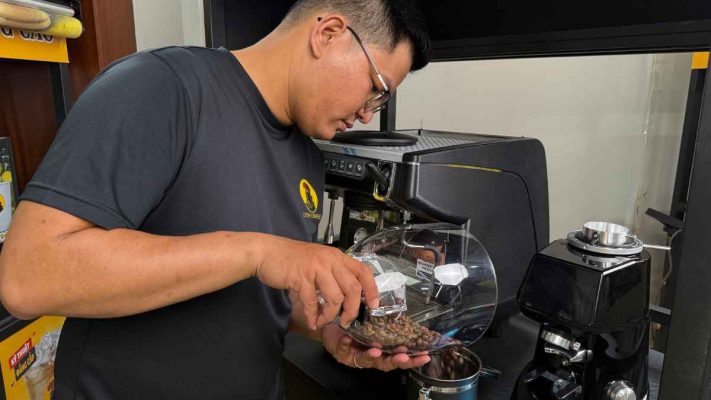 Tay đổ hạt cà phê Culi espresso vào hũ kín khí để bảo quản