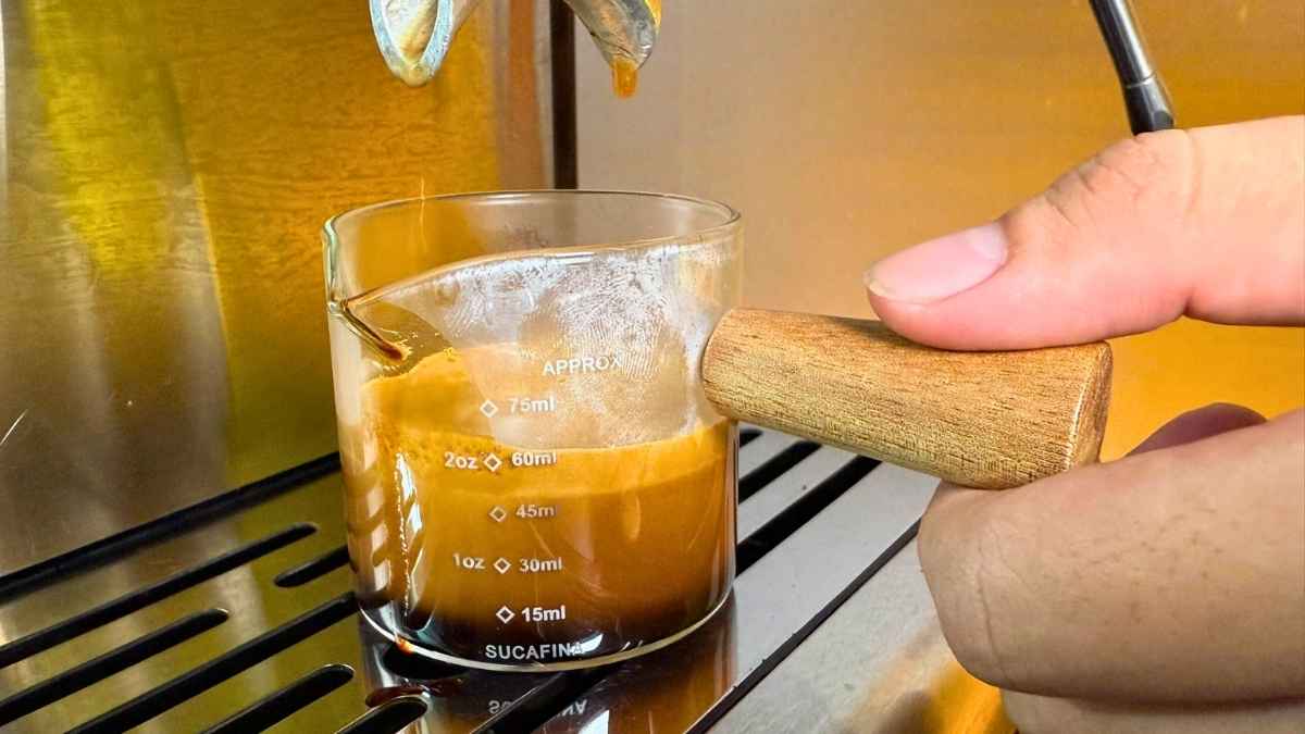 Barista dùng ly đong espresso cán gỗ để đo liều lượng chính xác