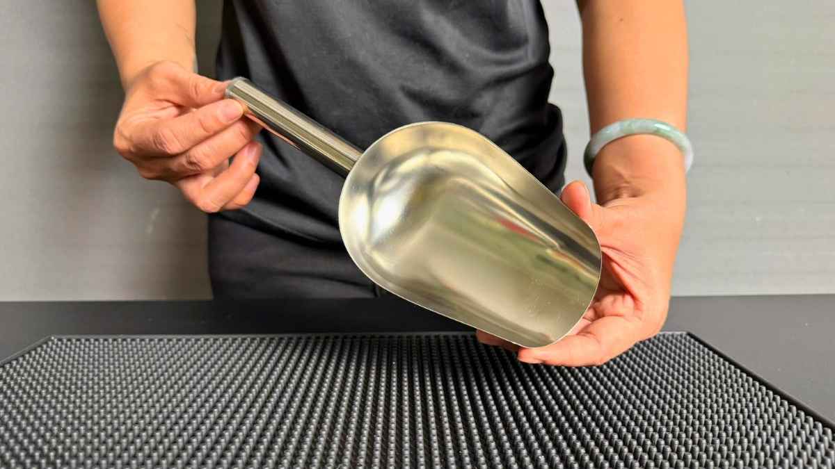 Barista dùng muỗng xúc đá inox để lấy đá viên cho trà sữa tại quán nhỏ