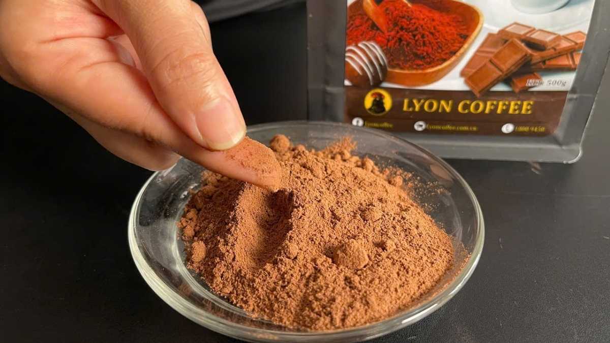 Muỗng bột chocolate nâu mịn trong hũ thủy tinh đặt cạnh sữa tươi và ca đánh sữa