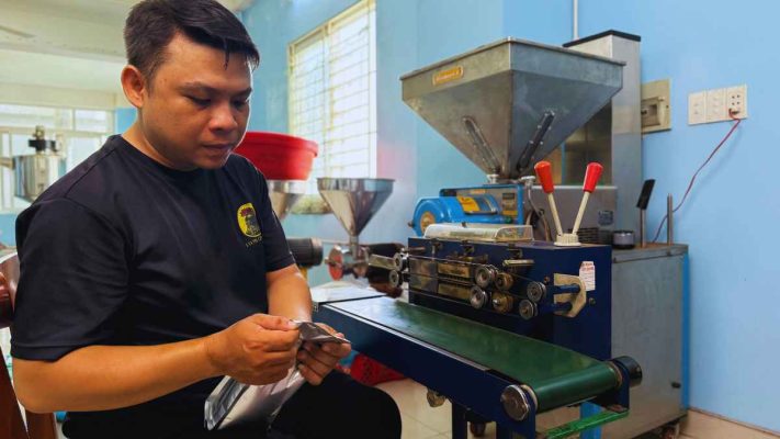 Tay đổ cà phê bột Culi rang xay sẵn vào hộp kín khí để bảo quản.