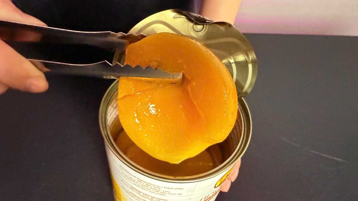 Barista Lyon Coffee gắp lát đào ngâm từ hộp để pha trà đào cam sả