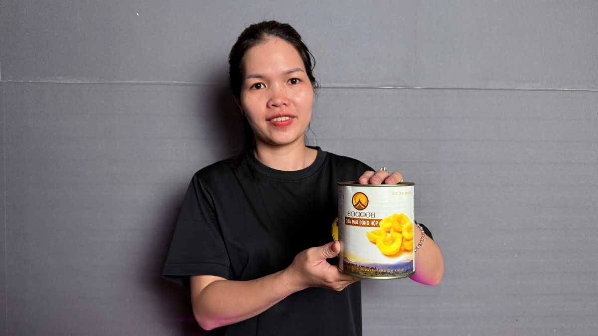 Hộp Đào ngâm Boddob Yot Doi 820g mở nắp, đặt cạnh ly trà đào vàng tươi