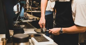Người đang pha cà phê bằng máy pha cà phê tự động tại nhà