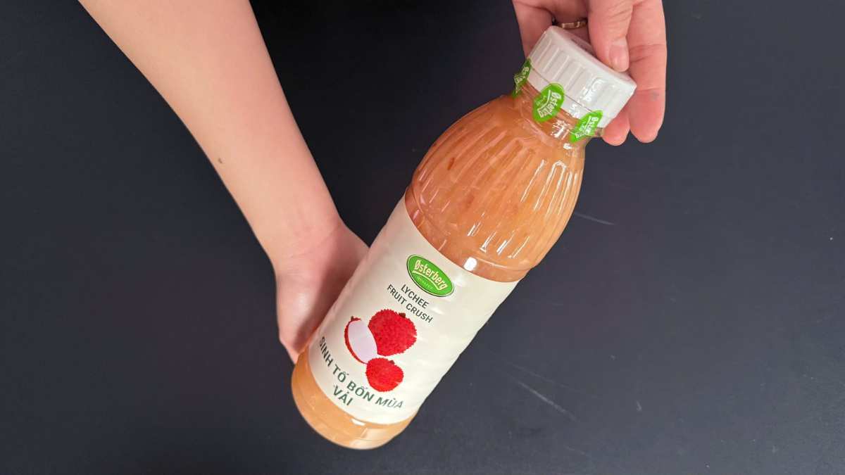 Logo Østerberg Đan Mạch bên cạnh chai Sinh tố Vải 1L trên nền sáng