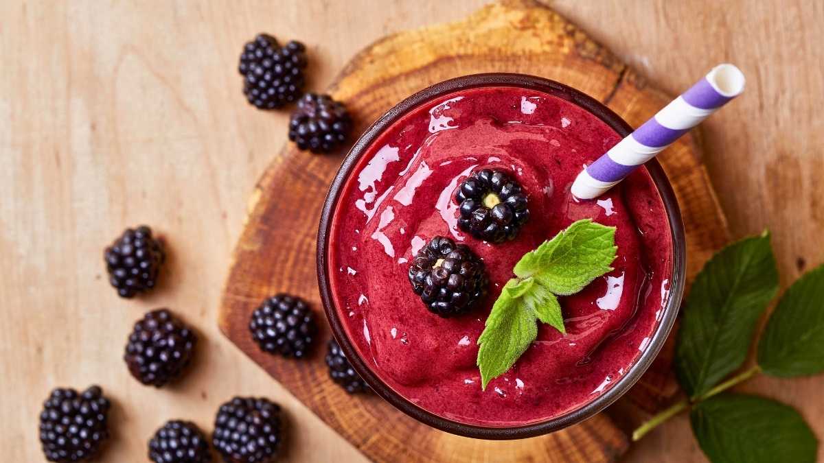 Ly trà dâu tằm đá lạnh màu tím tự nhiên, nền gỗ sáng và ánh nắng nhẹ