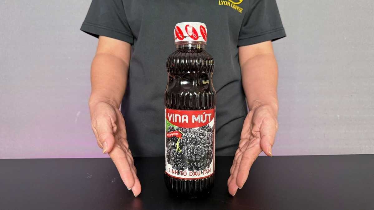 Chai Sinh Tố Vina Dâu Tằm 1L màu tím ánh đỏ đặt cạnh ly yogurt dâu tằm đá lạnh