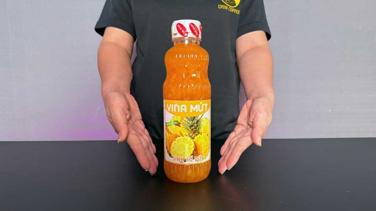 Chai Sinh Tố Vina Dứa 1L màu vàng tươi đặt cạnh ly soda dứa và lát dứa tươi