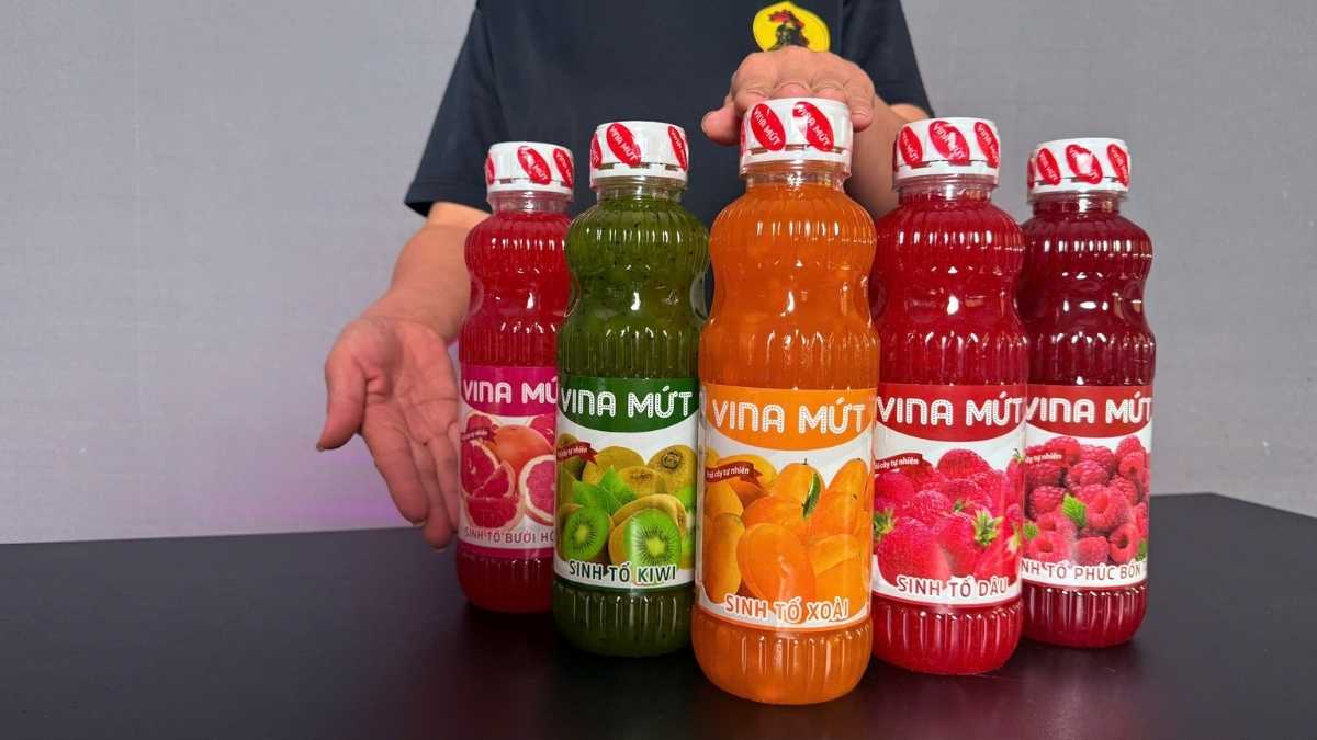 Logo Vina Mứt San Hô Xanh cạnh chai Sinh Tố Xoài trên nền sáng