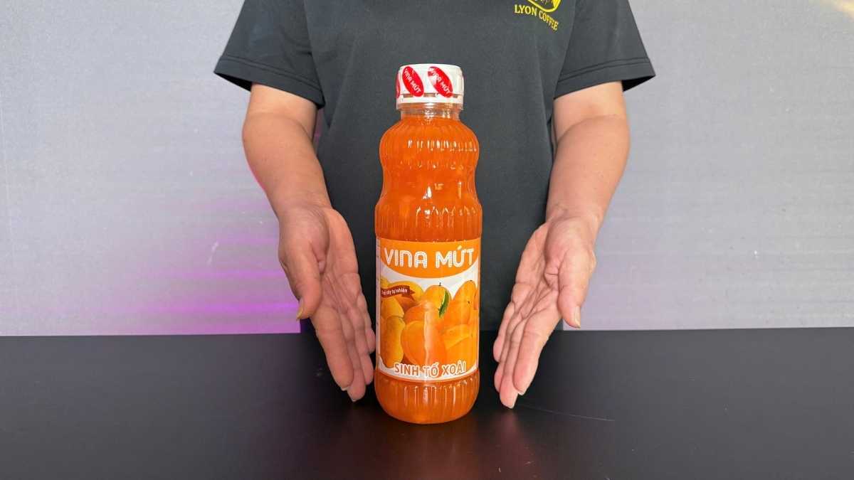 Chai Sinh Tố Vina Xoài 1L màu vàng tươi đặt cạnh ly smoothie xoài đá xay