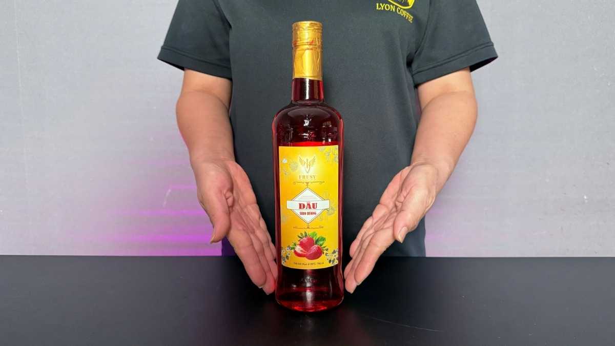 Chai Siro Frusy Dâu 1L đặt cạnh ly soda dâu đỏ hồng và dâu tươi cắt lát