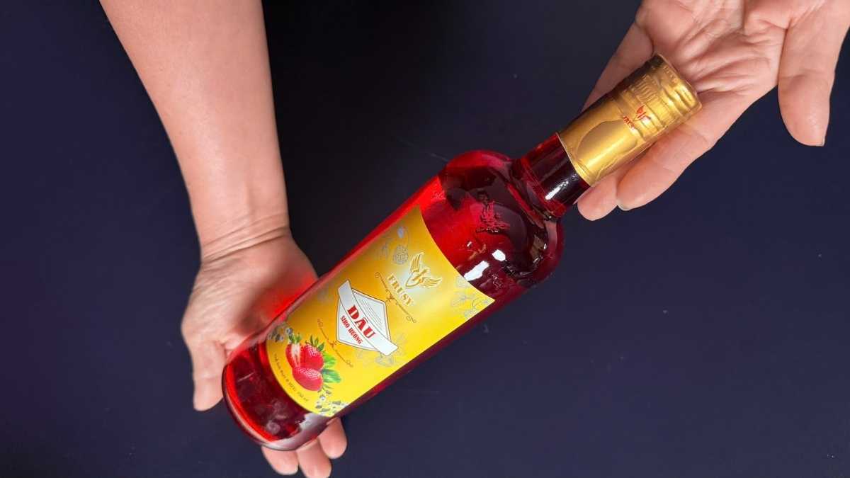 Chai thủy tinh Siro Frusy Dâu đặt trên nền gỗ sáng cùng dâu tươi