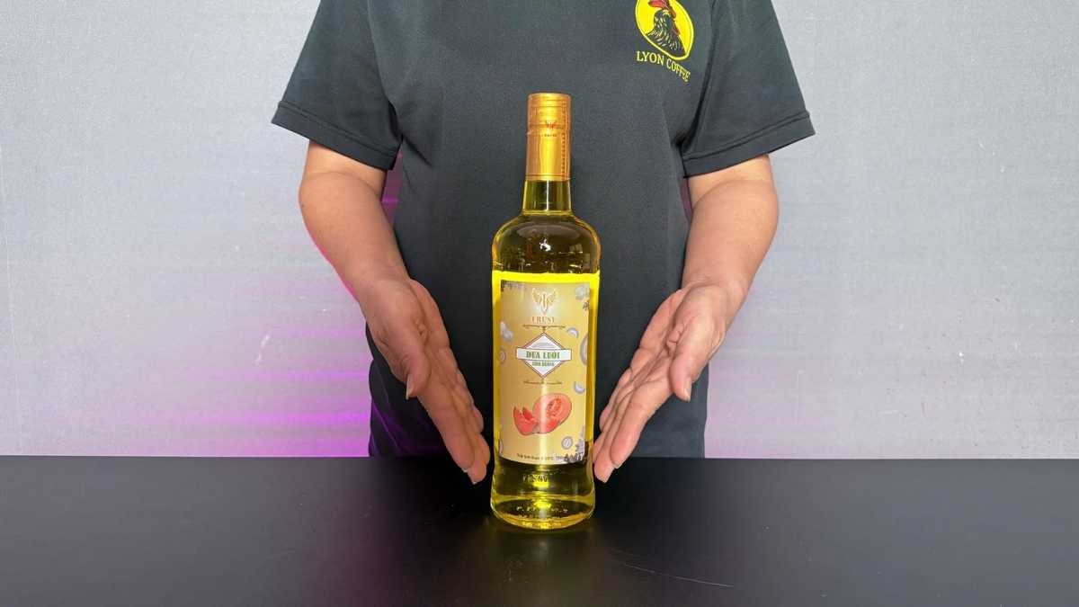 Chai Siro Frusy Dưa Lưới 1L đặt cạnh ly soda vàng nhạt và lát dưa lưới tươi