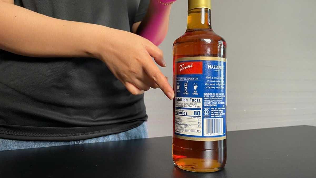 Siro Torani Hạt Dẻ rót vào ly thủy tinh nhỏ, màu nâu hổ phách trong suốt