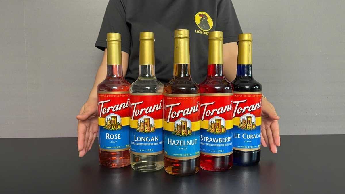 Barista Lyon Coffee pha hồng trà sữa hạt dẻ với chai Torani đặt cạnh