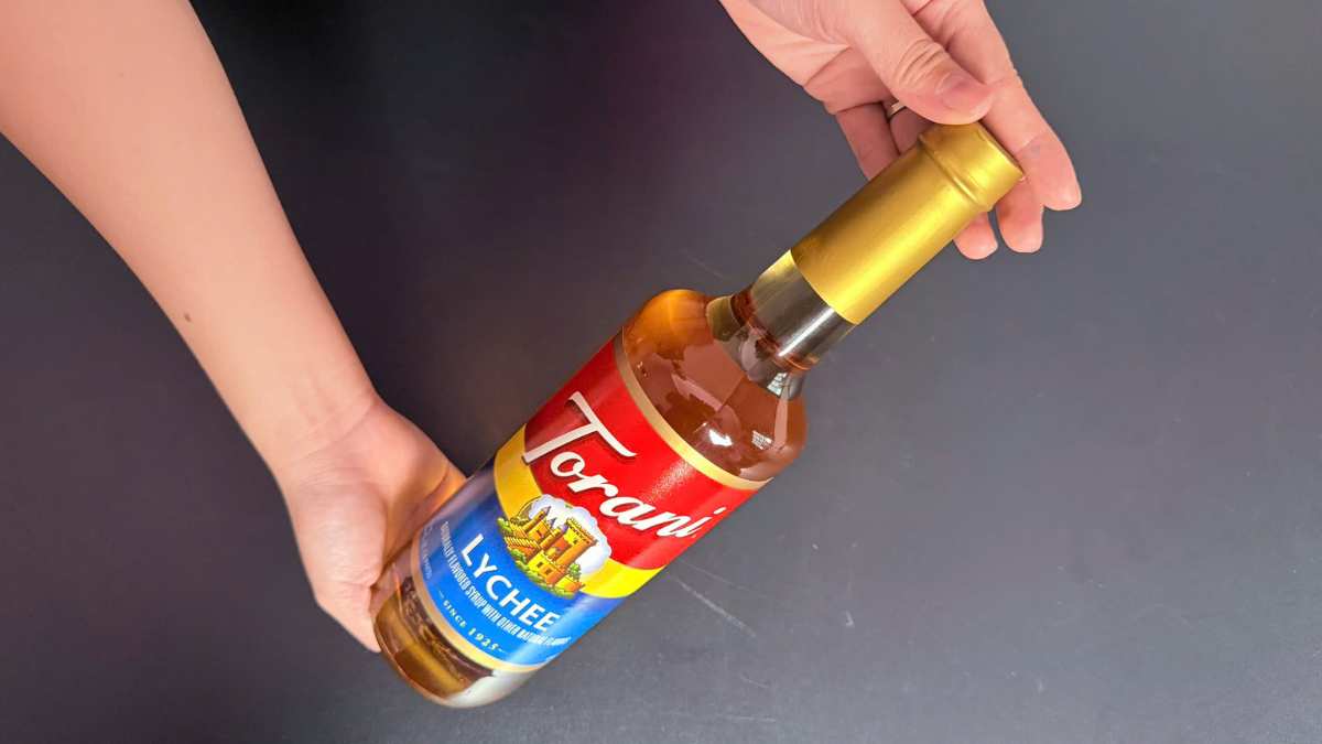 Chai Torani Lychee đặt cạnh logo Torani USA trên nền bar sang trọng