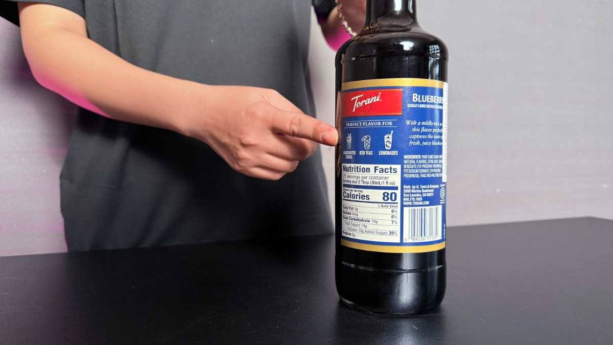 Cận cảnh giọt siro Torani Việt Quất rơi vào ly nước trong ánh sáng lạnh