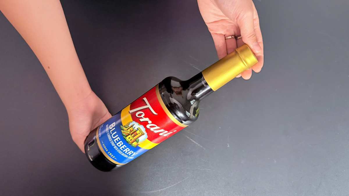 Logo Torani USA cạnh chai Torani Việt Quất trên nền bar sang trọng