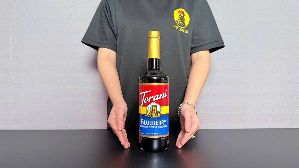 Ly soda việt quất Torani với đá lạnh và quả việt quất tươi trên nền gỗ sáng