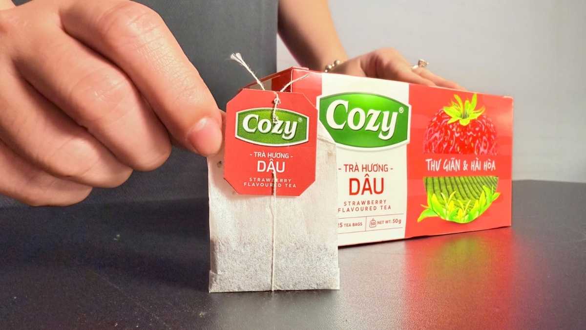Túi trà Cozy Dâu pha trong ly thủy tinh, nước trà màu hổ phách ánh đỏ