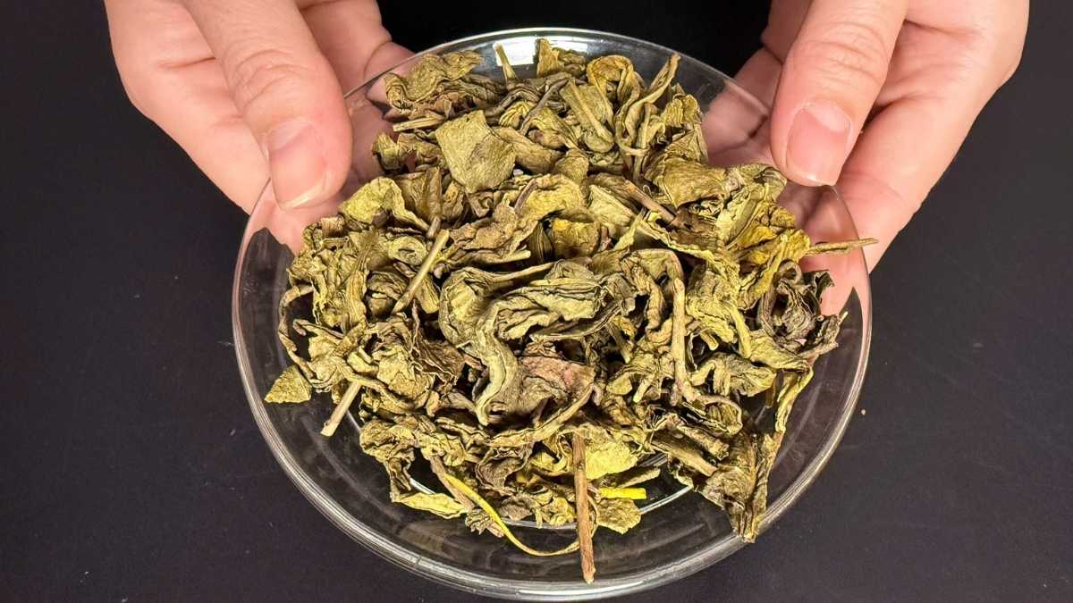 Lá trà xanh và hoa lài khô trộn đều trong khay gỗ, nền sáng tự nhiên