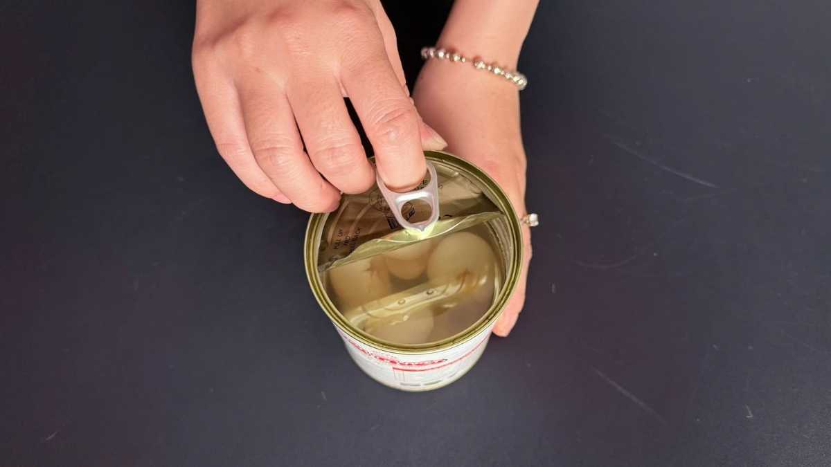 Hũ vải ngâm mở nắp, đặt cạnh tủ lạnh mini và ly soda lạnh